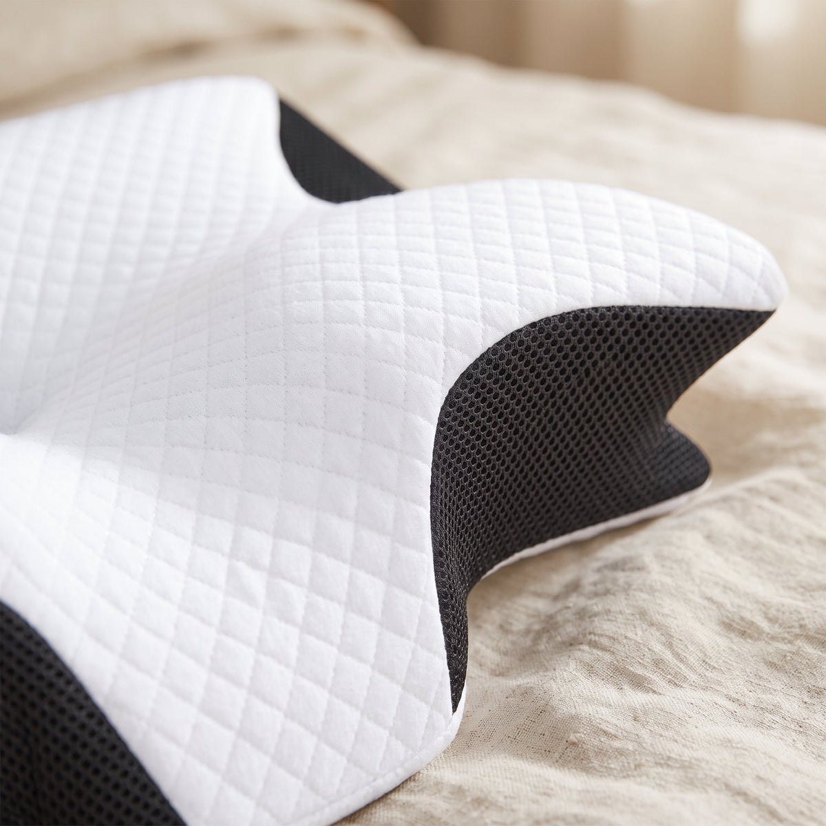 Gros plan sur la housse matelassée blanche et le côté en maille noire d’un oreiller cervical. Image